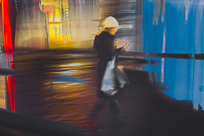 In Conversation a woman walking through Oslo city streets at night while talking on her phone — ICM photography cycling wall art print by Douglas Carr at Oslo Art Prints