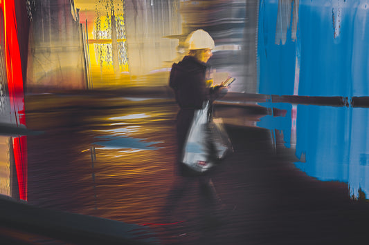 In Conversation a woman walking through Oslo city streets at night while talking on her phone — ICM photography cycling wall art print by Douglas Carr at Oslo Art Prints